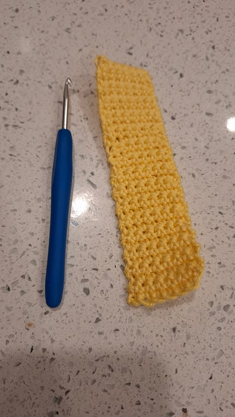 yellow bookmark, pile of crocheted items, rainbow book cozy, yellow pocket, blue coaster, set of pockets