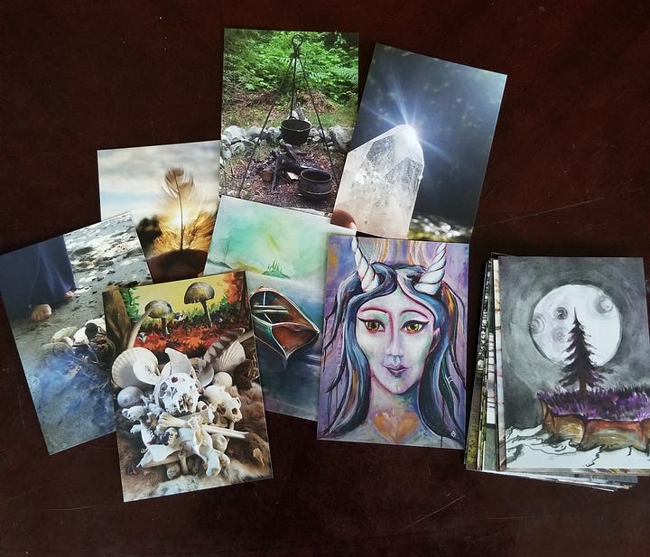 Various oracle cards spread face up across a table and a stacked deck face down beside a tea cup