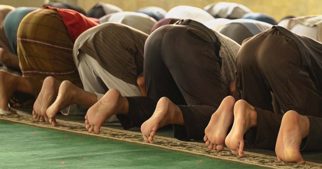 A group of men standing in a line on a rug A group of men standing in a line on a rug