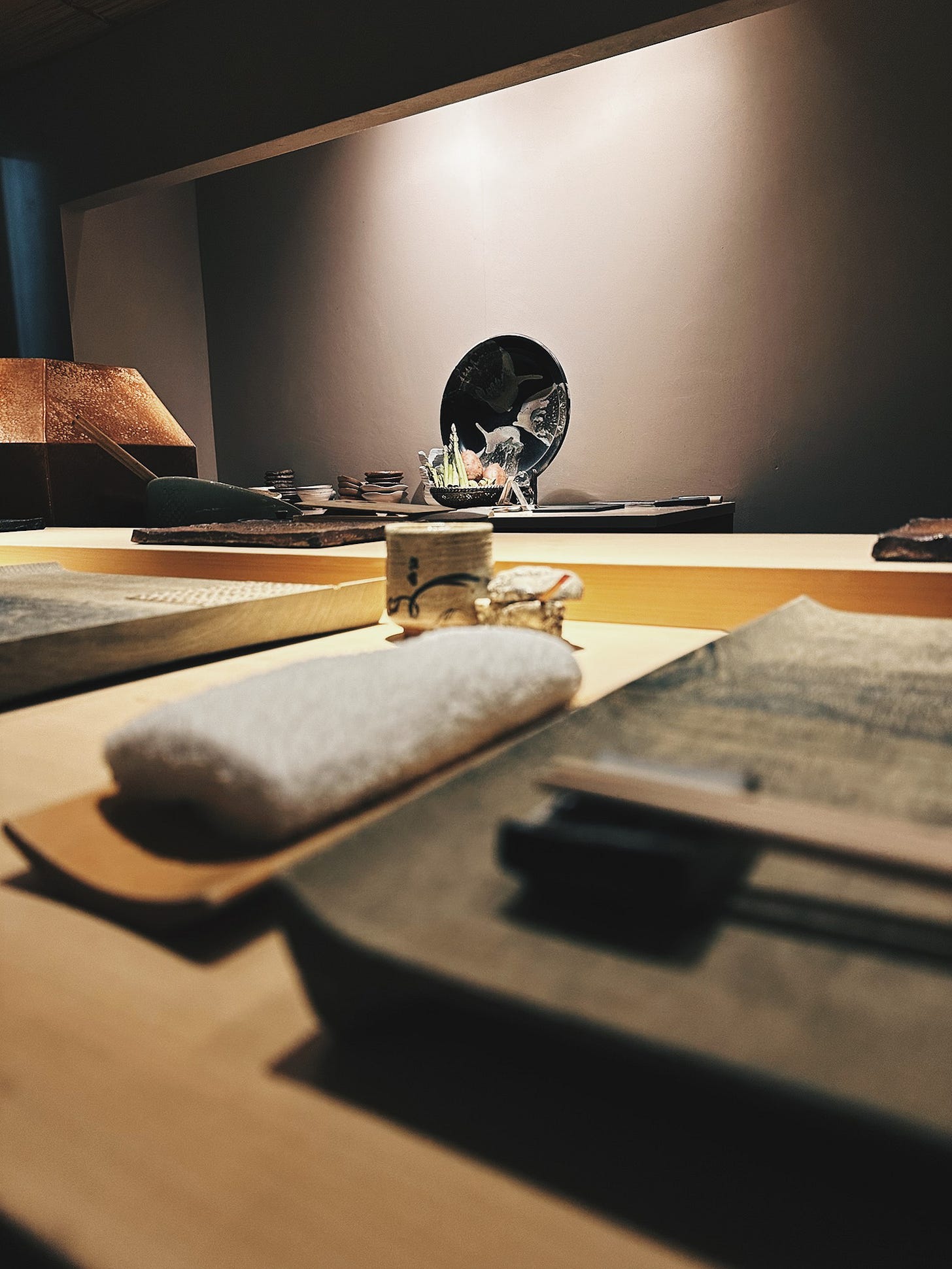 Intimate hinoki wood counter setting at Tempura Araki in Susukino, Sapporo, with place settings and lacquered display piece in the background Intimate hinoki wood counter setting at Tempura Araki in Susukino, Sapporo, with place settings and lacquered display piece in the background