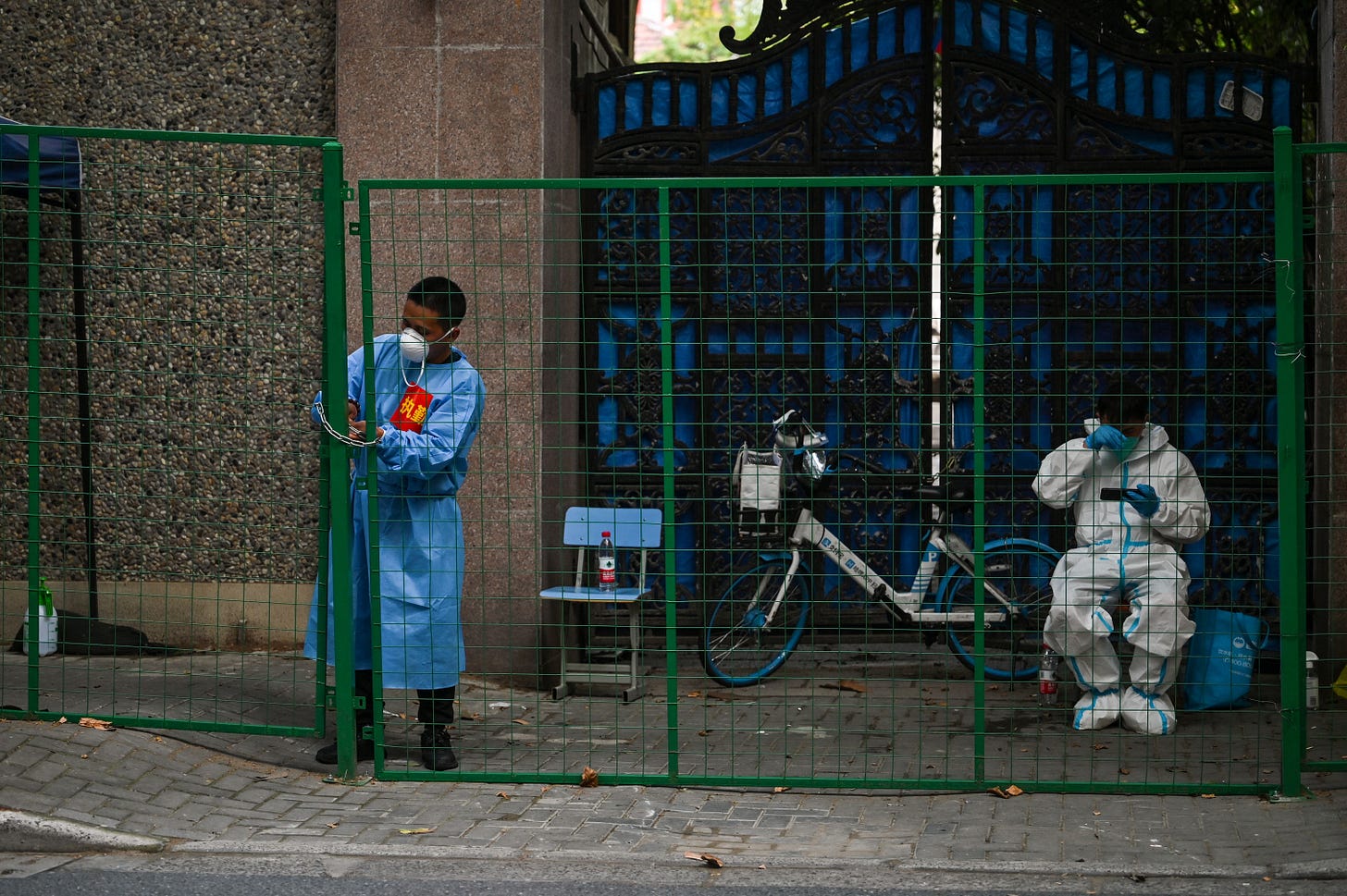 A worker wearing protective gear padlocks a fence to secure a residential area under a Covid-19 lockdown in the Xuhui district of Shanghai on June 16, 2022. (Photo by Hector RETAMAL / AFP) (Photo by HECTOR RETAMAL/AFP via Getty Images) A worker wearing protective gear padlocks a fence to secure a residential area under a Covid-19 lockdown in the Xuhui district of Shanghai on June 16, 2022. (Photo by Hector RETAMAL / AFP) (Photo by HECTOR RETAMAL/AFP via Getty Images)