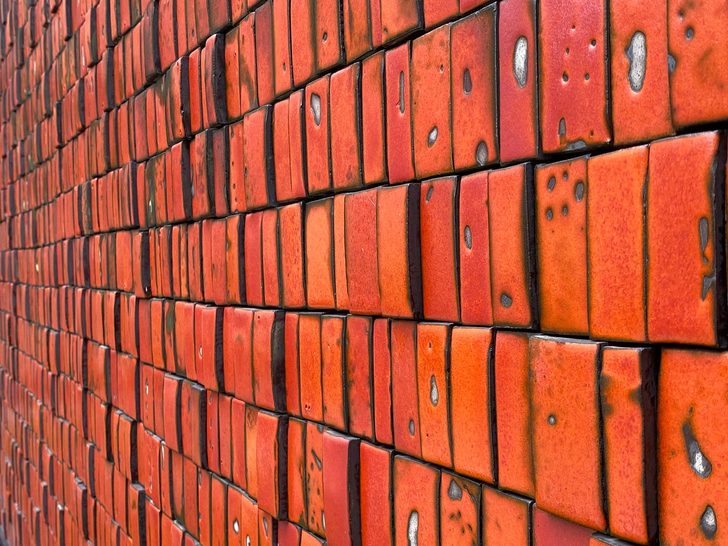 Detail view of Doyle Lane, Mutual Savings and Loan Mural, as if you’re standing close to the mural and looking to the side. This view shows that the tiles are of varying depth and have blackened sides. Detail view of Doyle Lane, Mutual Savings and Loan Mural, as if you’re standing close to the mural and looking to the side. This view shows that the tiles are of varying depth and have blackened sides.