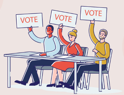 Three people behind a desk all holding a hand up in the air with a banner saying vote.