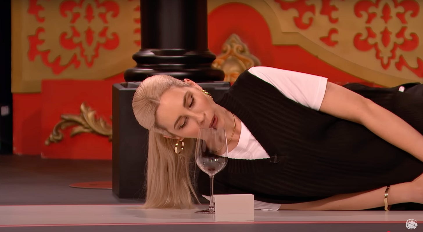 Stevie Martin lying on her side, spitting raisins into a wine glass. Stevie Martin lying on her side, spitting raisins into a wine glass.