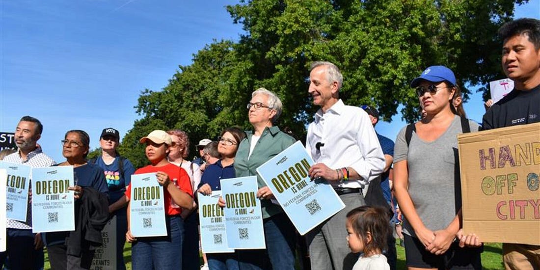 Mayor Wilson and Governor Kotek hold signs at rally saying "Oregon is home."