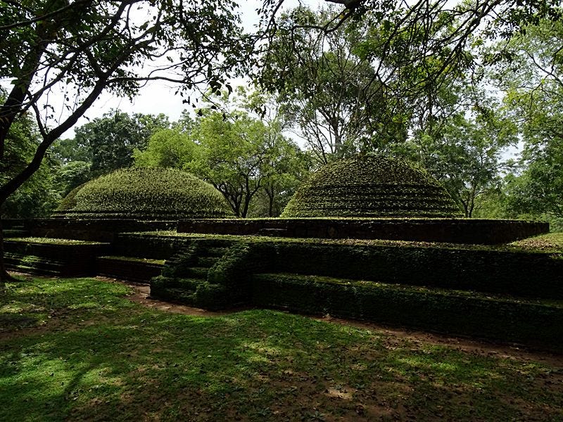 Ancient moss-covered stupas surrounded by dense green vegetation