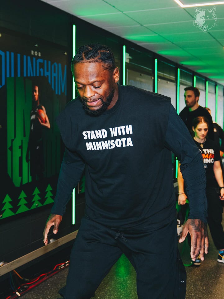 Very tall basketball players wearing black t-shirts that say Stand With Minnesota in white block letters