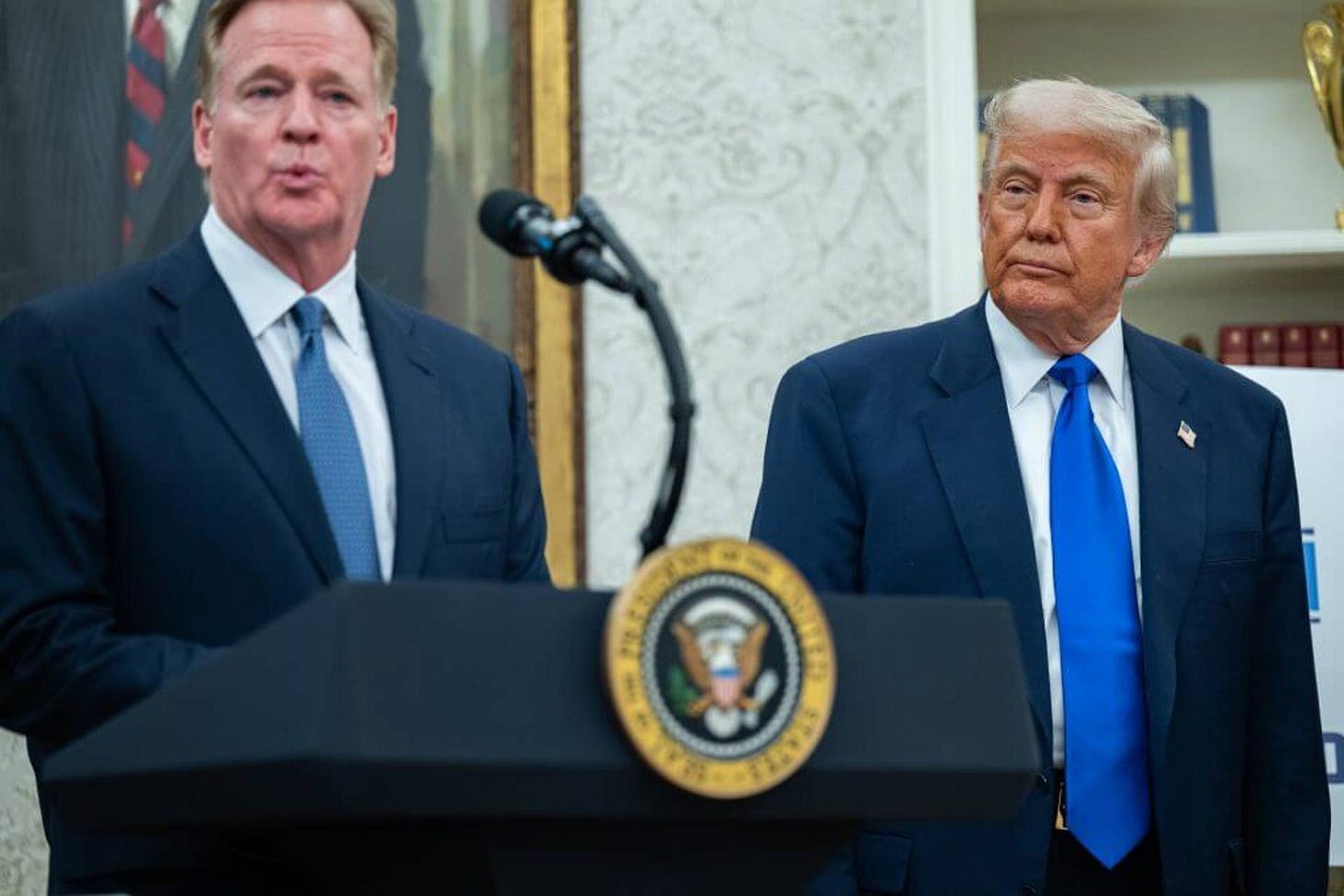 Roger Goodell speaking at a lectern in the Oval Office as President Donald Trump looks on. Roger Goodell speaking at a lectern in the Oval Office as President Donald Trump looks on.