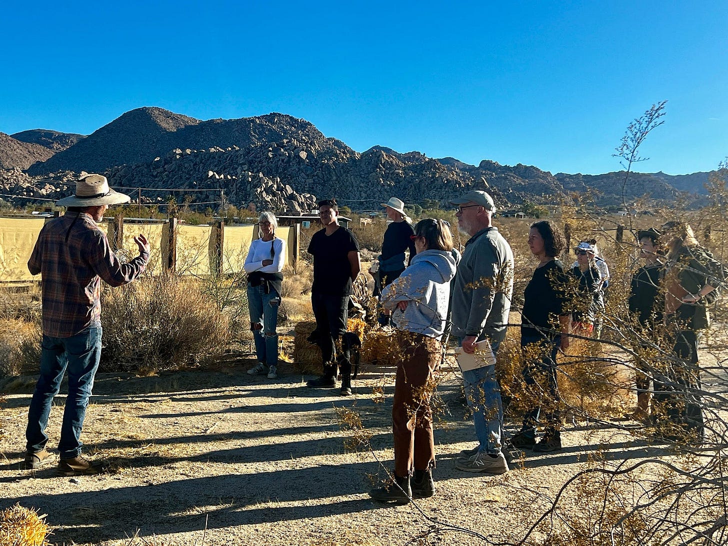 Photo of a man in a sun hat facing a group outside