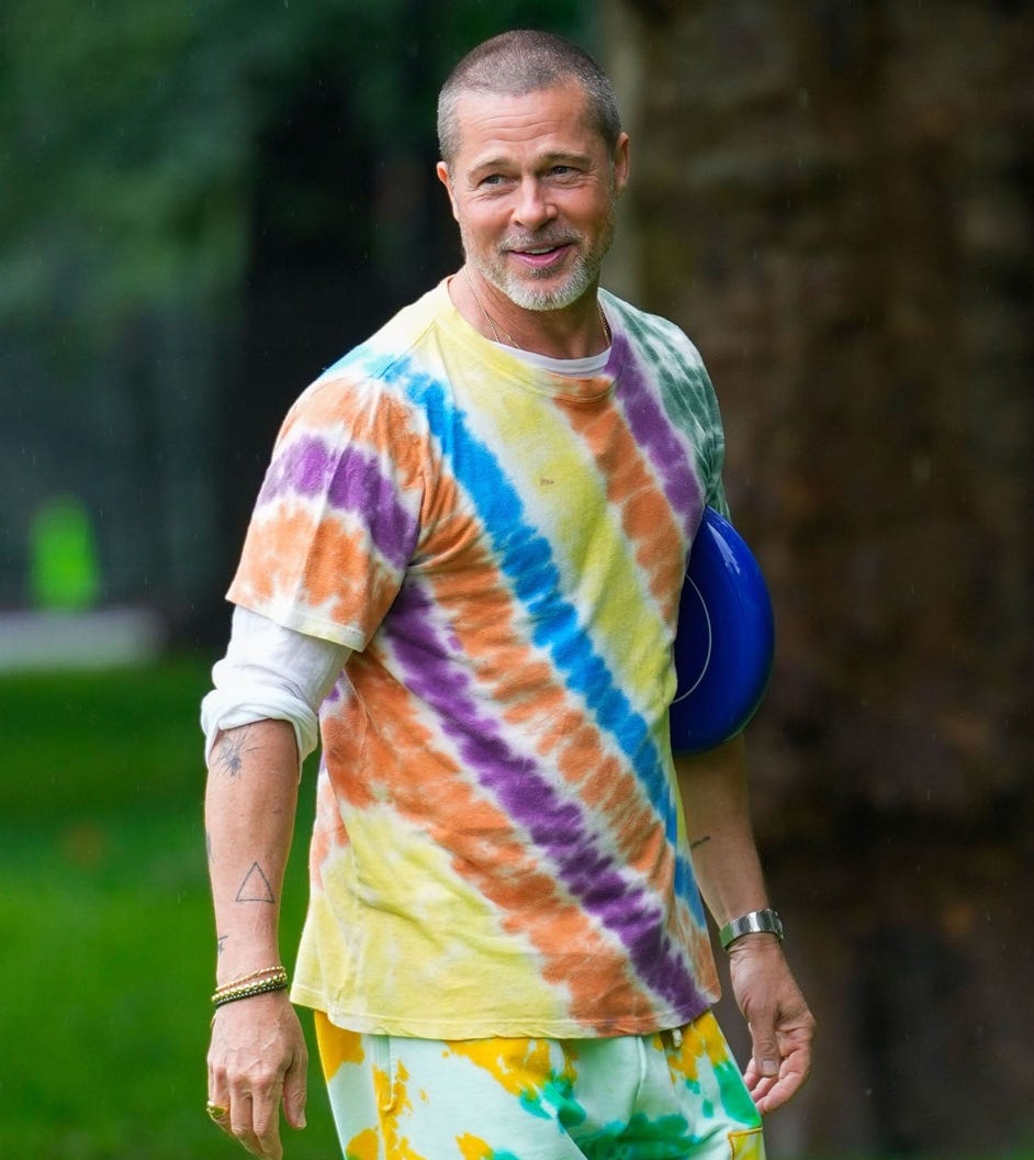 Brad Pitt in tie-dye clothing in a park.
