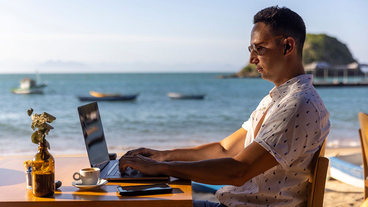 Digital nomad founder working on a laptop by the beach, representing the rise of lean remote startups and location-independent entrepreneurship