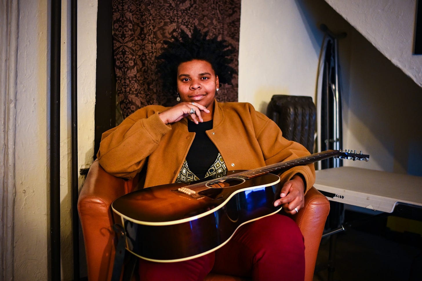 A woman sits with a guitar in her lap