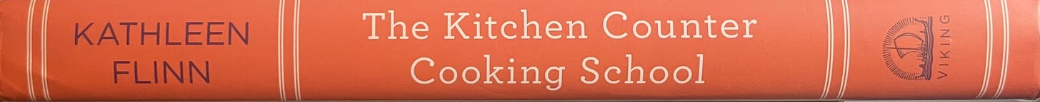 Book spine for The Kitchen Counter Cooking School by Kathleen Flinn. Bright orange cover.