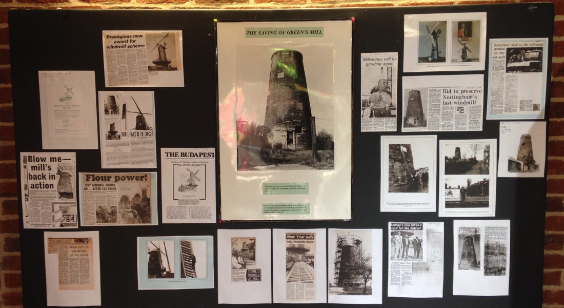 A blackboard with black and white newspaper clippings and photos of Green's Windmill A blackboard with black and white newspaper clippings and photos of Green's Windmill