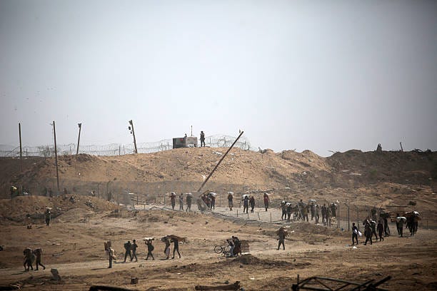 Palestinians carry bags at a food distribution point run by the US and Israeli-backed Gaza Humanitarian Foundation group, near the Netsarim corridor...