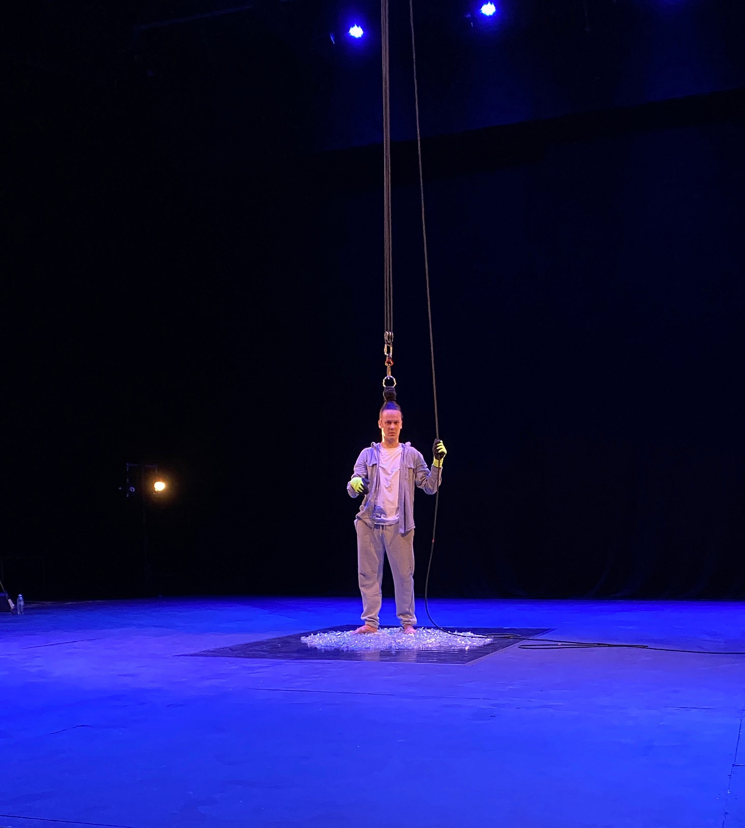 man with top knot attached to cable standing on glass