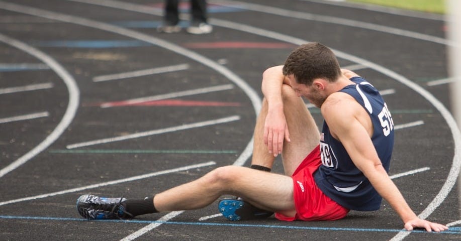 a man sitting on the ground in a track a man sitting on the ground in a track
