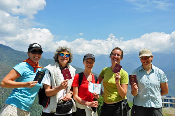 Group of 5 white women hikers holding up their passports and smiling. Group of 5 white women hikers holding up their passports and smiling.
