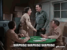 a group of men in military uniforms are sitting around a table with cards . a group of men in military uniforms are sitting around a table with cards .