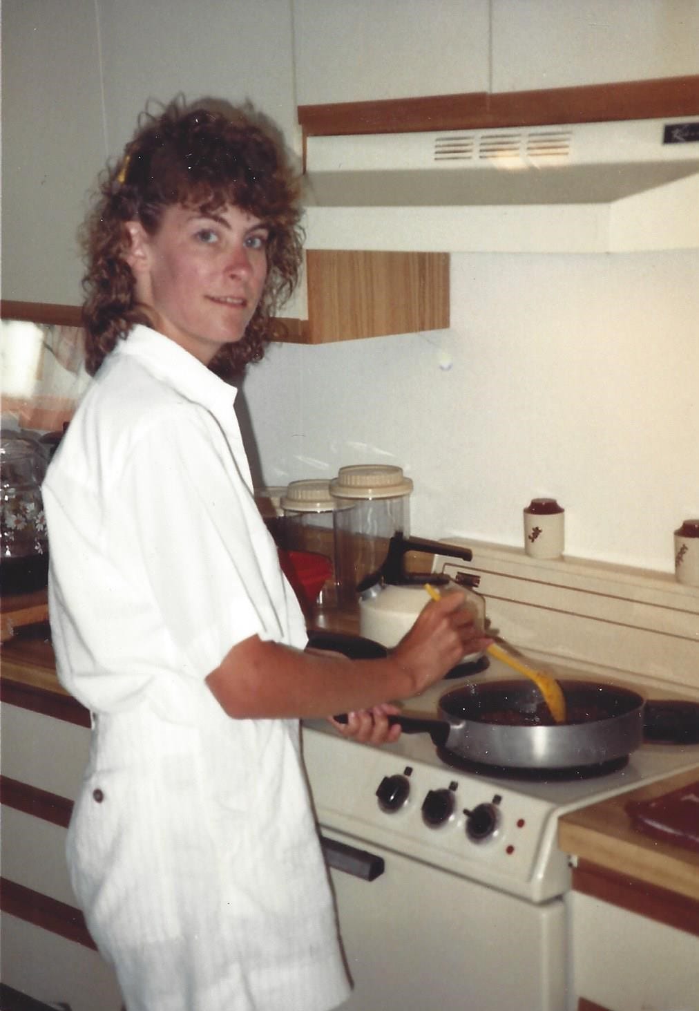 20-something woman stands at a stove and browns ground beef in a frying pan 20-something woman stands at a stove and browns ground beef in a frying pan