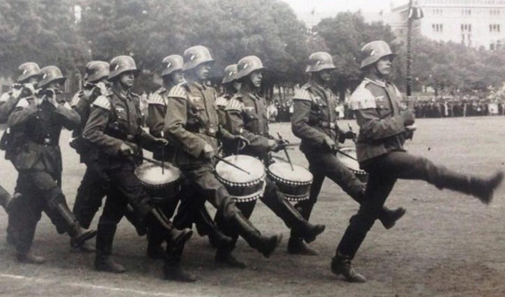 A group of men marching with drums

AI-generated content may be incorrect.