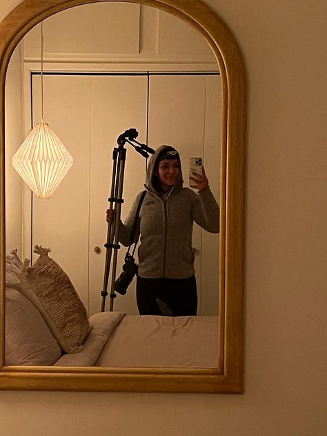 One row of three photos, left to right: Selfie of woman smiling and holding her digital camera, the sun streaming in through the living room and falling on her face; Photo of woman smiling holding up a copy of her book printed on a stack of computer printer paper; Mirror self-portrait of author in main house secondary bedroom wearing multiple layers of clothing, a headlamp, camera strung on her shoulder, and holding a camera tripod that is taller than her 5’2 frame.
