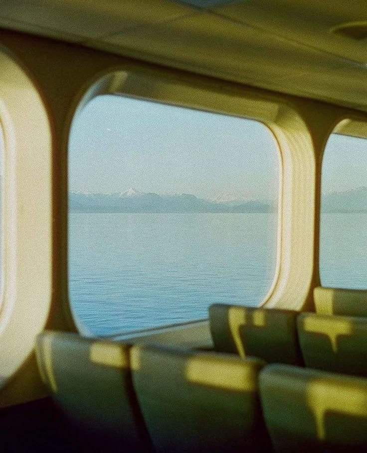 This may contain: the view from inside an airplane looking out at water and mountains in the distance, with green seats on either side This may contain: the view from inside an airplane looking out at water and mountains in the distance, with green seats on either side