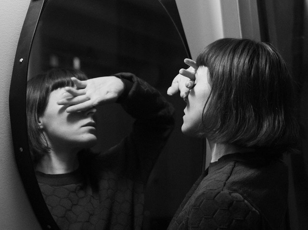 woman in black long sleeve shirt standing in front of mirror woman in black long sleeve shirt standing in front of mirror