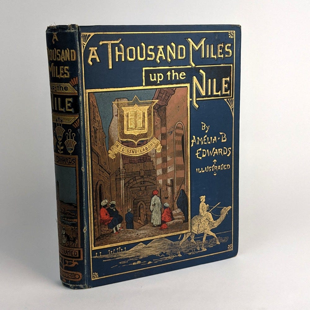 Elaborate, printed blue/gold cover for A Thousand Miles up the Nile (1877), featuring Egyptian scenes and a woman riding a camel