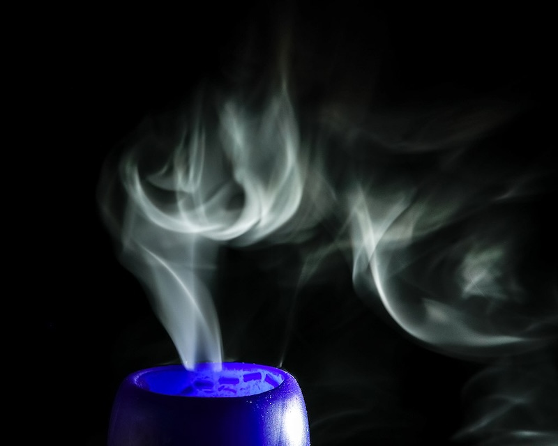 smoke from a cobalt blue candle that's burned out is making an attractive pattern against a black background. smoke from a cobalt blue candle that's burned out is making an attractive pattern against a black background.