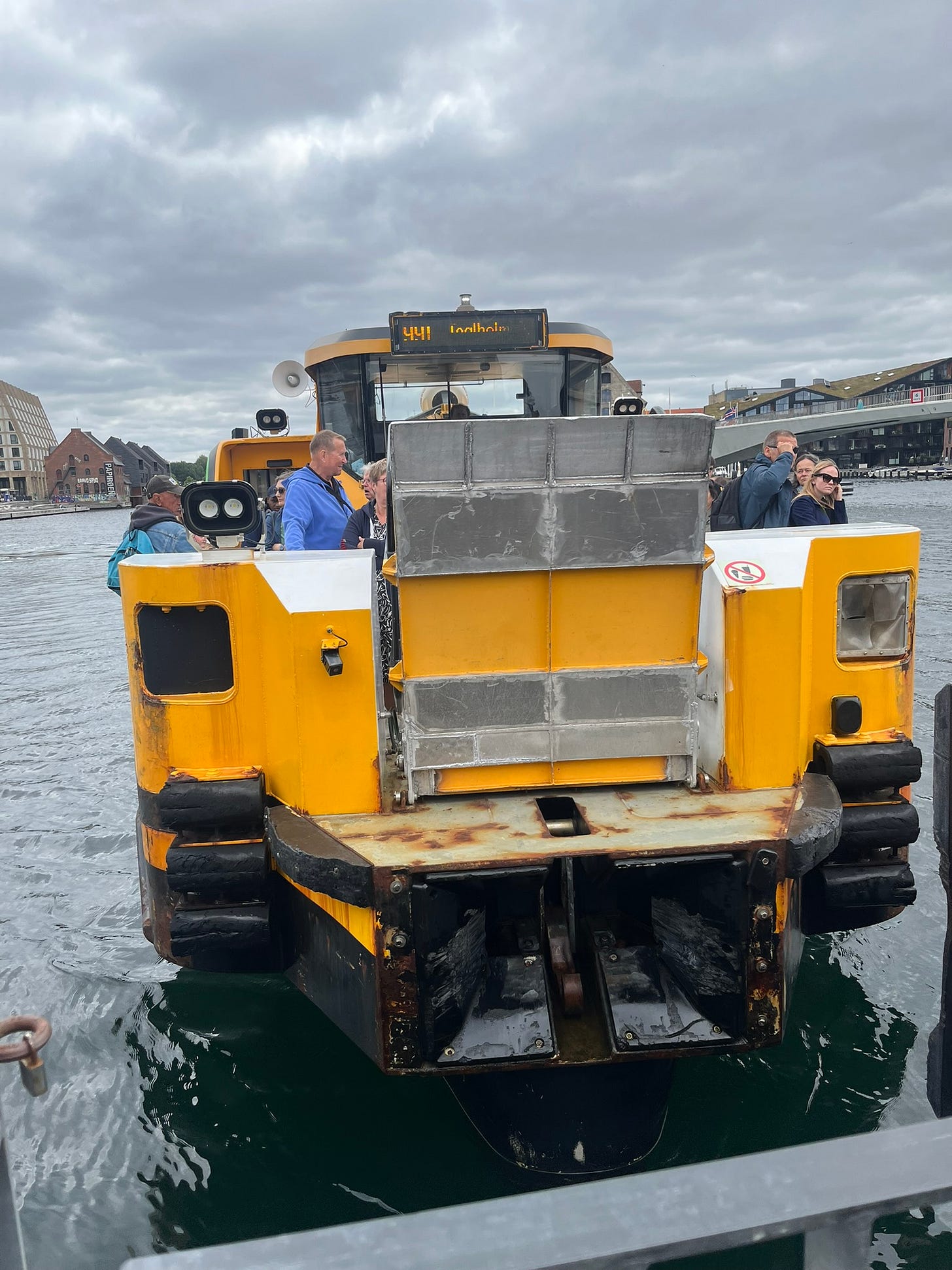 A yellow boat, about to dock at a stop, using a short drawbridge