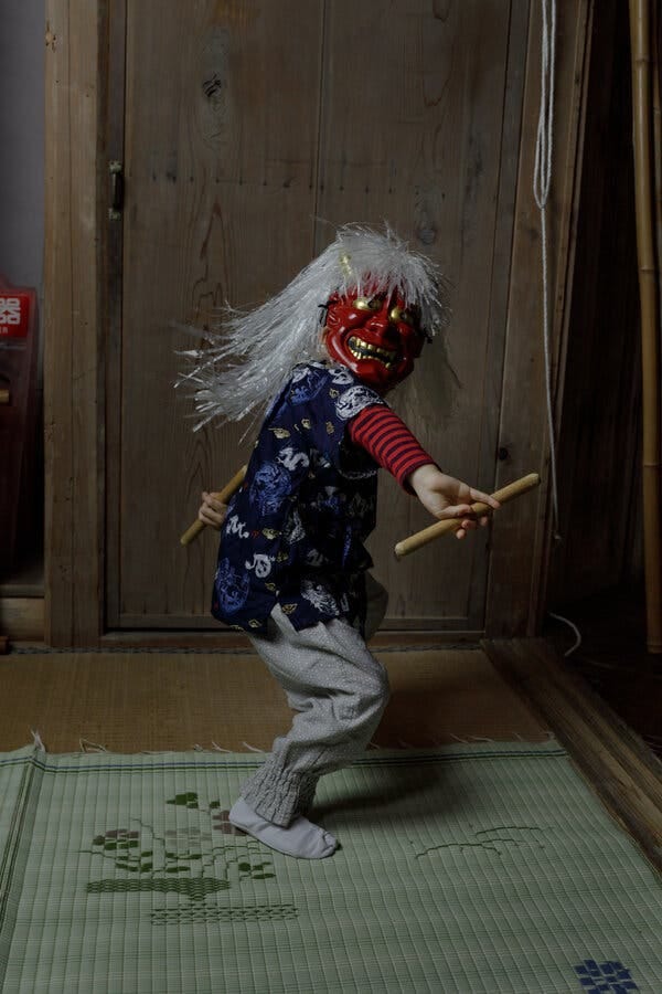 A boy wearing a red mask twirls sticks in his hands. A boy wearing a red mask twirls sticks in his hands.