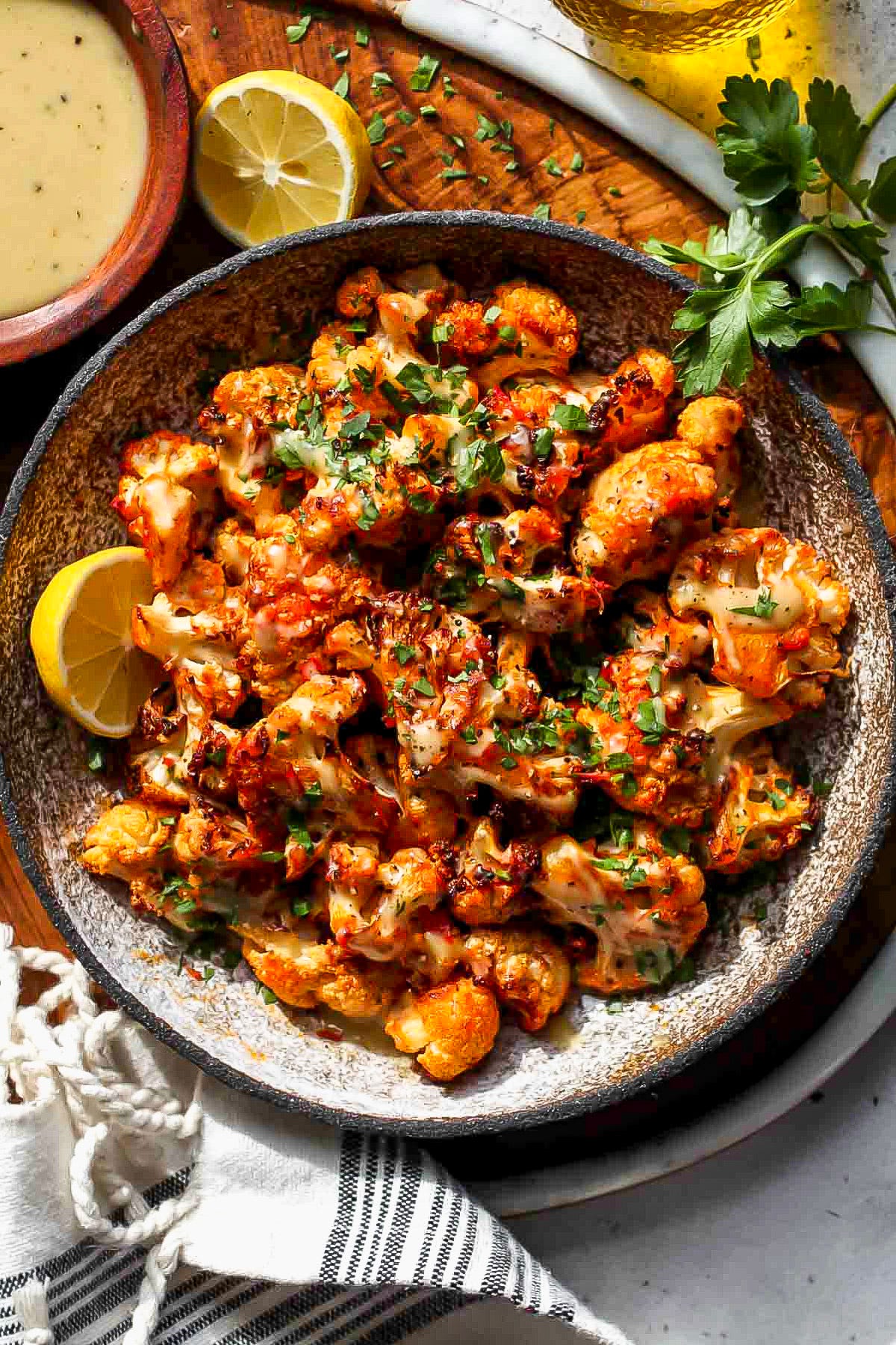 Moroccan cauliflower with tahini honey styled in a grey bowl topped with chopped parsley