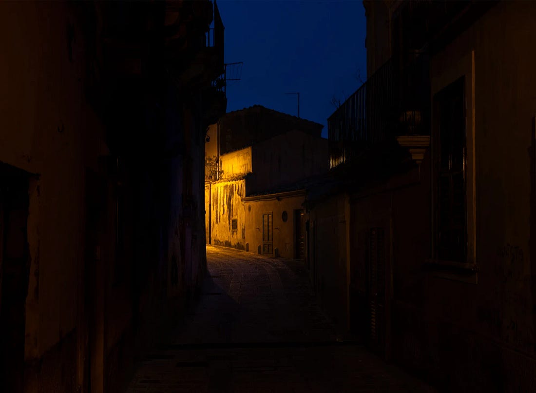 A dark alley in Ragusa Ibla at night, lit by a single streetlamp. A dark alley in Ragusa Ibla at night, lit by a single streetlamp.