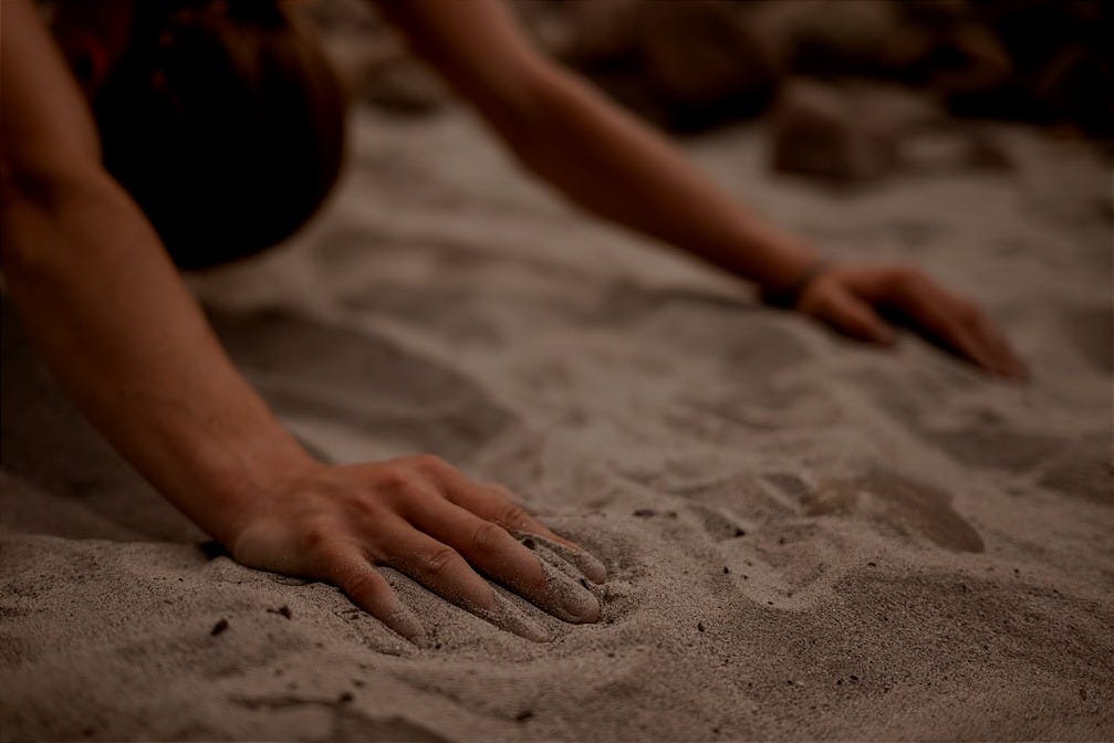 a person reaching for something in the sand