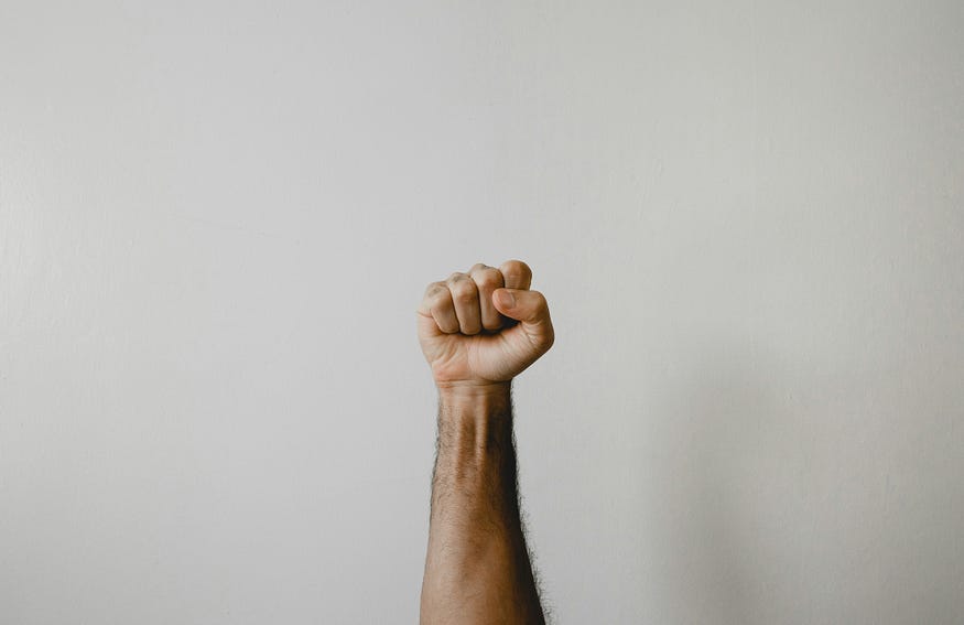 A fist is raised in outrage, against a white background.