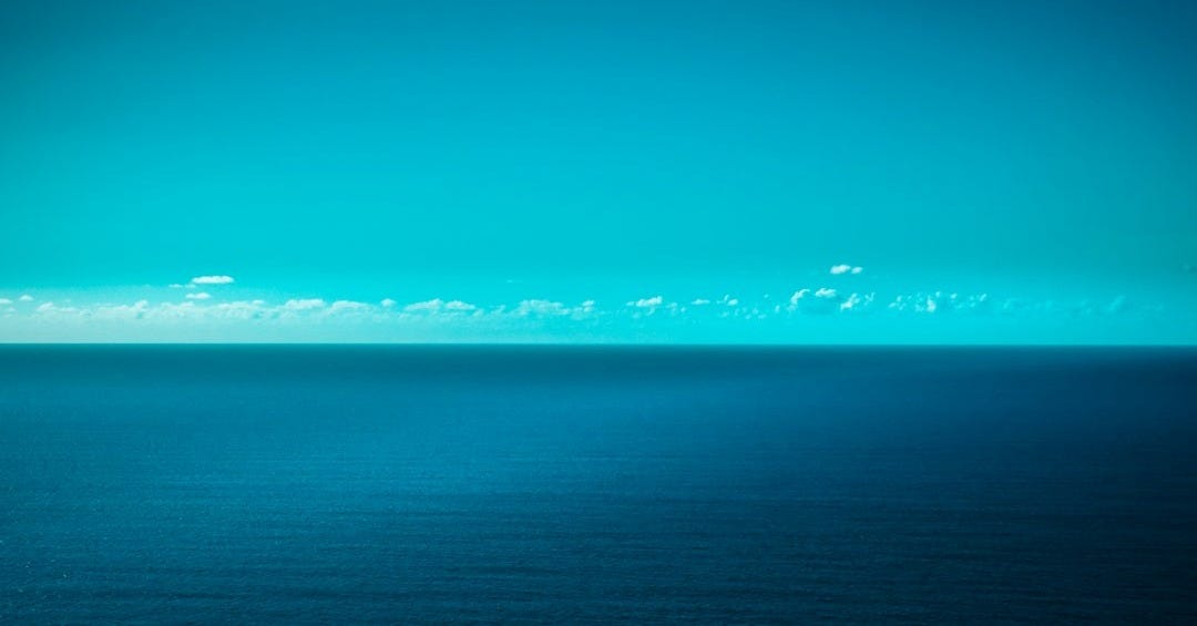 a large body of water sitting under a blue sky