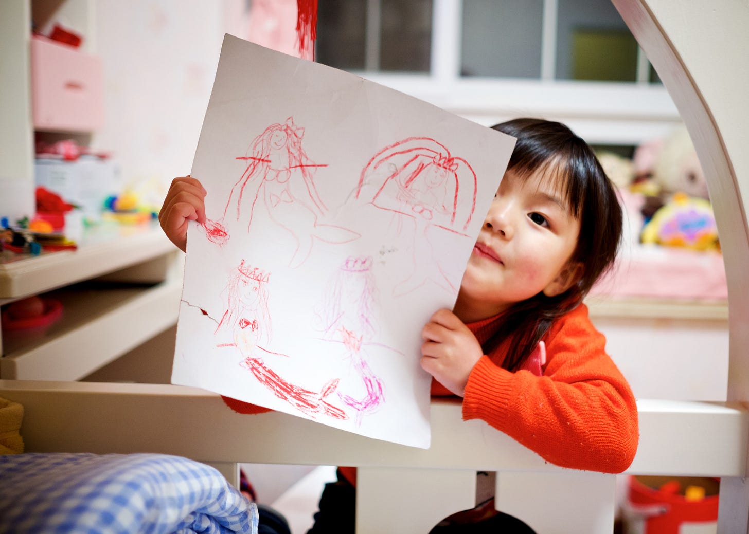 preschool asian girl holding up a crayon drawing of a mermaid preschool asian girl holding up a crayon drawing of a mermaid
