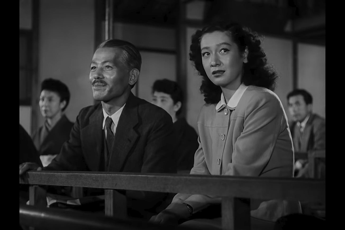 Persistence without Force: Mrs. Miwa bows to Somiya in the audience while Noriko lowers her head, registering her father’s separateness and the fragility of their shared world. Persistence without Force: Mrs. Miwa bows to Somiya in the audience while Noriko lowers her head, registering her father’s separateness and the fragility of their shared world.