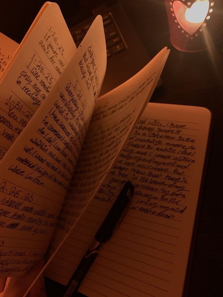 This may contain: an open book with writing on it next to a lit candle and a light bulb