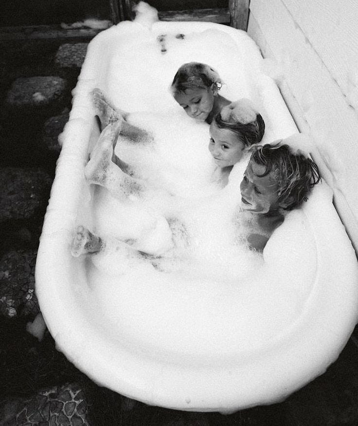 This may contain: three children are sitting in the bathtub together