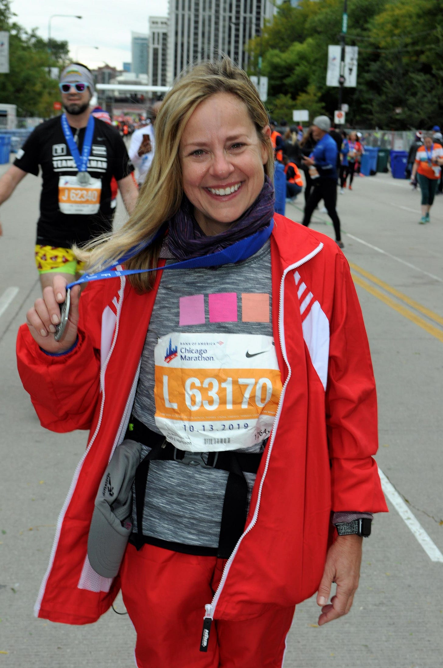 A sandy-blonde woman with hair below her shoulders smiles with tearful eyes after just crossing the Chicago Marathon finish line in 2019. The subject of the photo is Christine Wolf, a memoir-writing coach who lives north of Chicago. 