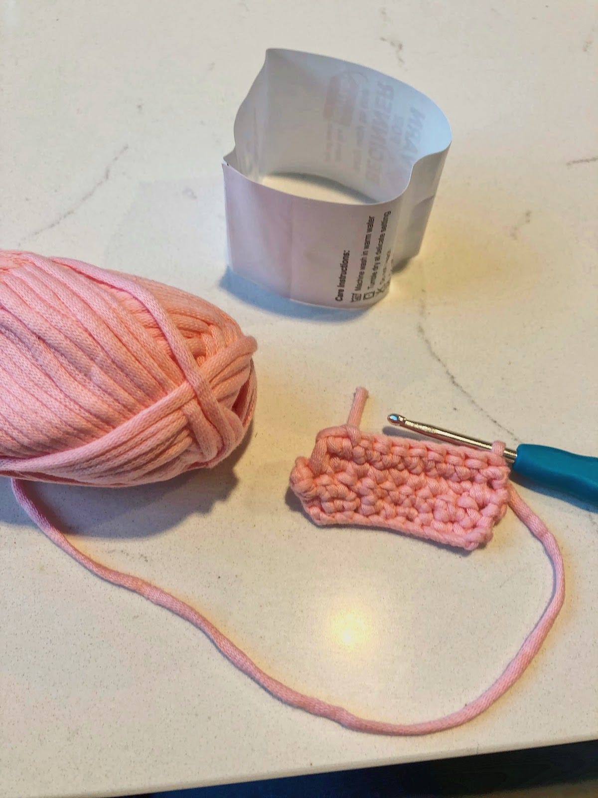 Pink yarn and a crochet needed with the beginning of some practice chains
