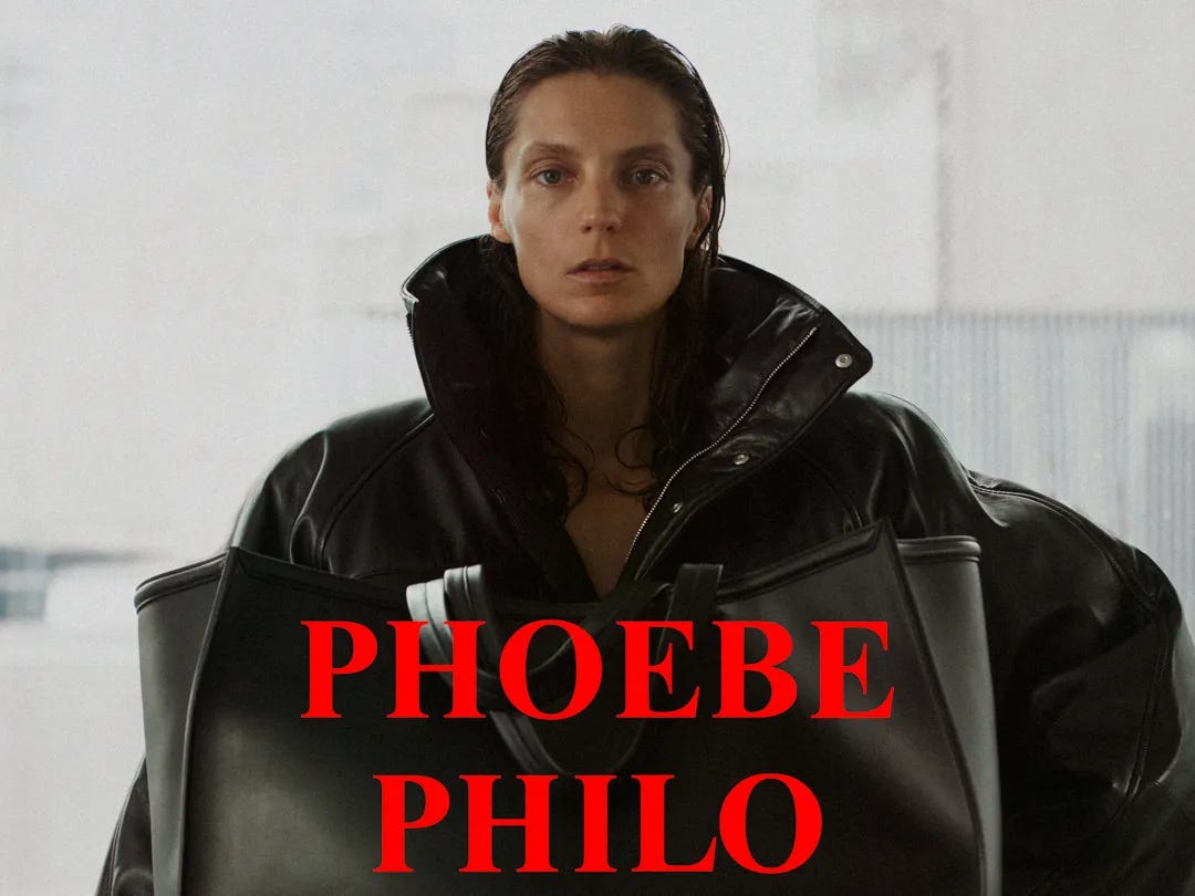 A woman with slicked back hair is photographed from the waist up wearing an oversied leather coat.