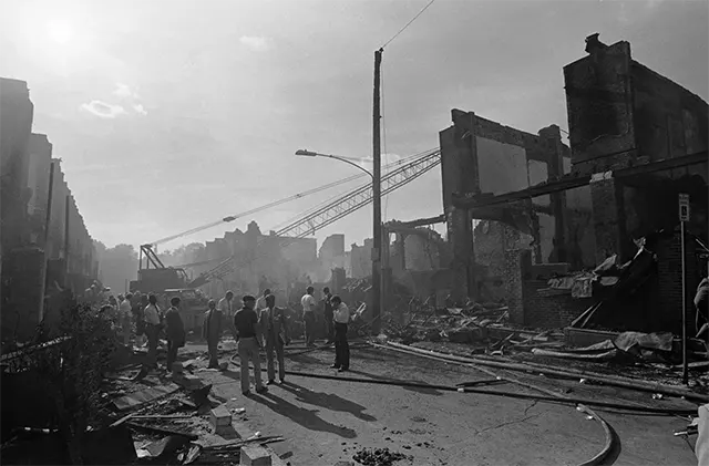 Smoke-filled skies over the ravaged neighborhood, hours after the controversial police operation. Smoke-filled skies over the ravaged neighborhood, hours after the controversial police operation.