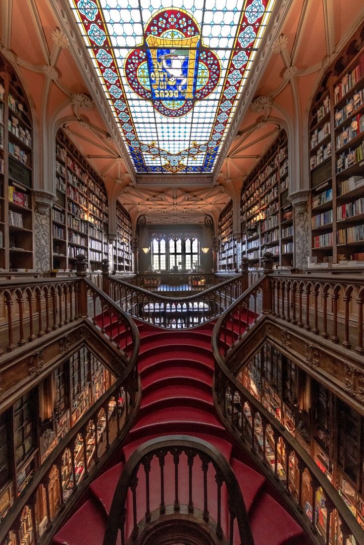 This may contain: the interior of a large library with many books on shelves and stained glass ceilinging