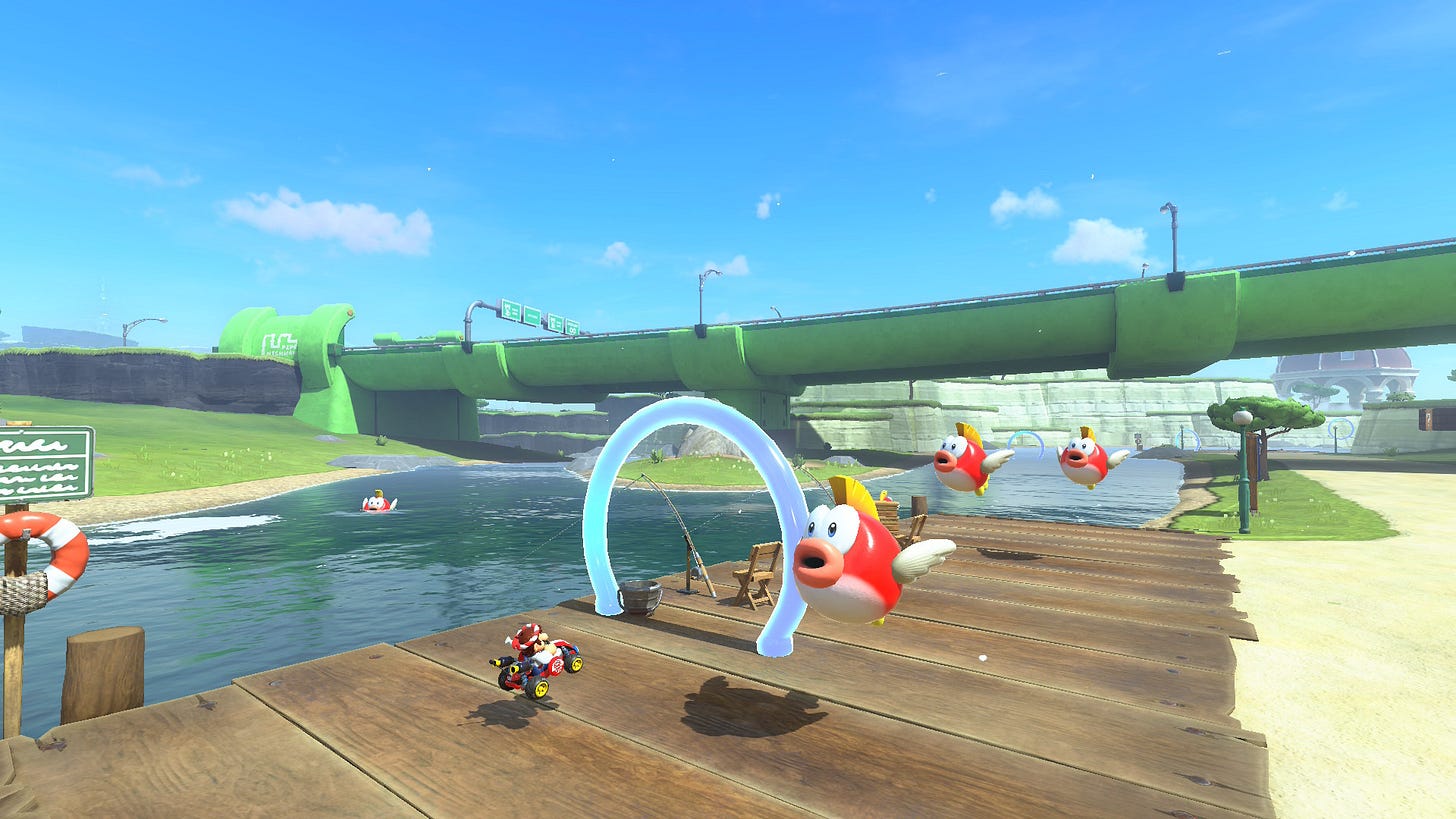 Video game screenshot showing a Mario kart driver on a dock with a big green pipe serving as a highway bridge in the background