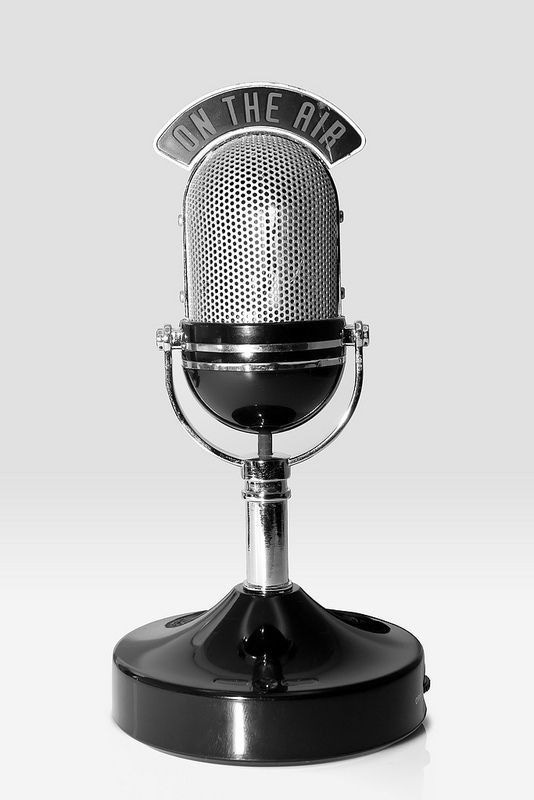 This may contain: an old fashioned microphone with the words on the air written in black and white letters