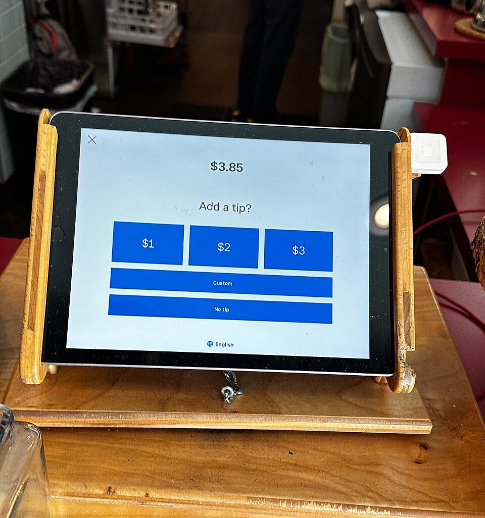 Coffee-shop payment tablet offering tips of $1, $2, or $3, alongside custom-tip and no-tip options. Coffee-shop payment tablet offering tips of $1, $2, or $3, alongside custom-tip and no-tip options.