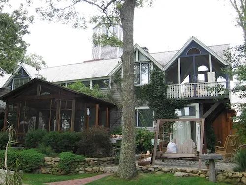 Photo of a nice house with a terrace, surrounded by trees.